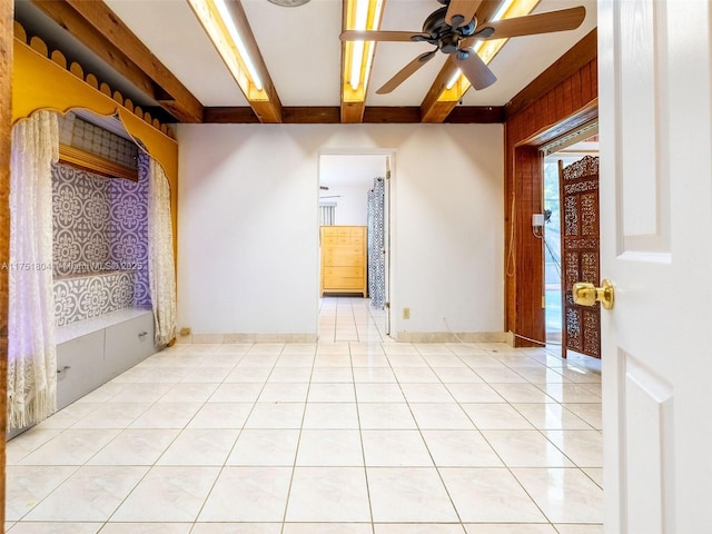 unfurnished room with beamed ceiling, light tile patterned flooring, a ceiling fan, and baseboards