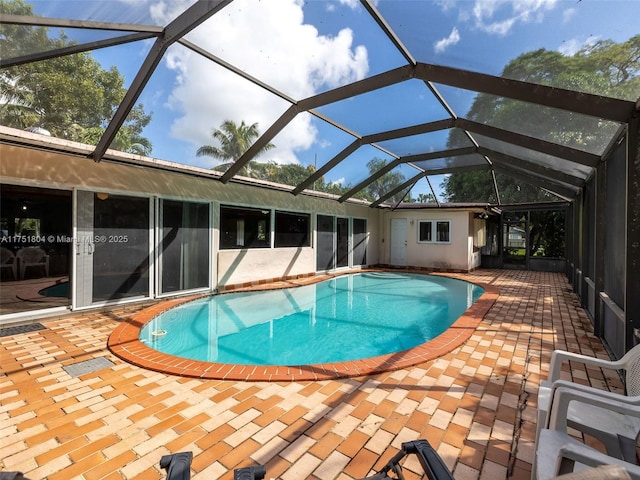 outdoor pool featuring glass enclosure and a patio