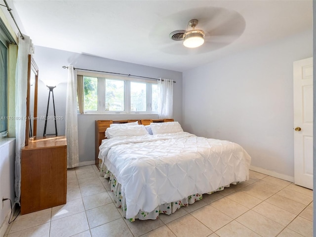 bedroom with light tile patterned floors, a ceiling fan, and baseboards