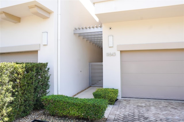 doorway to property featuring stucco siding and a garage