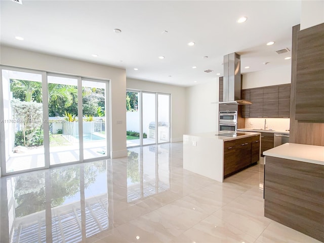 kitchen featuring an island with sink, light countertops, appliances with stainless steel finishes, modern cabinets, and island range hood