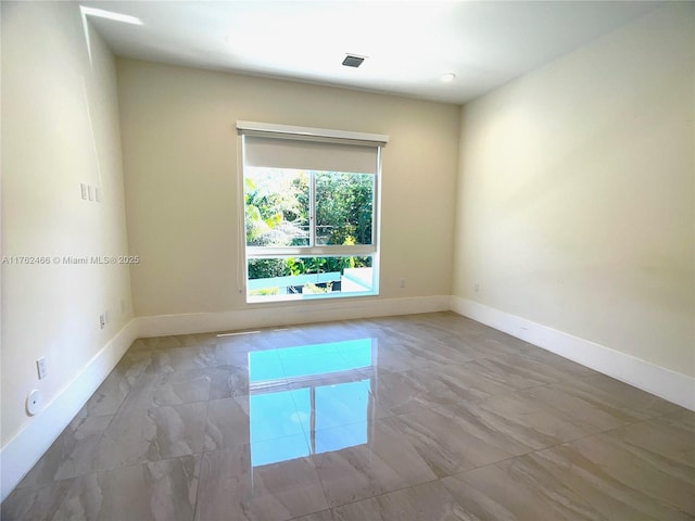 unfurnished room with visible vents, marble finish floor, and baseboards