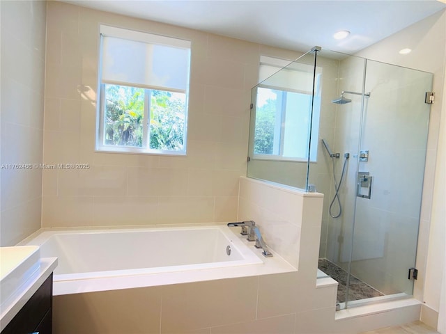 bathroom featuring a bath, a shower stall, and vanity