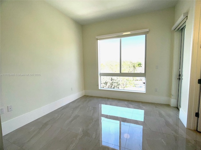 empty room featuring marble finish floor and baseboards