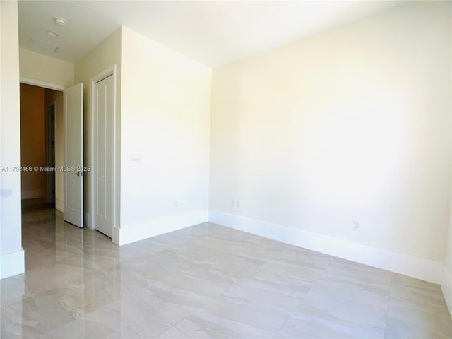 spare room featuring baseboards and marble finish floor