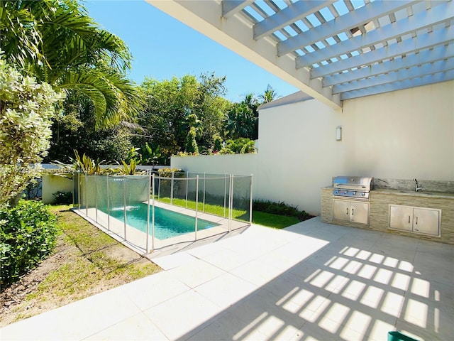 view of pool featuring fence, exterior kitchen, area for grilling, a patio, and a sink