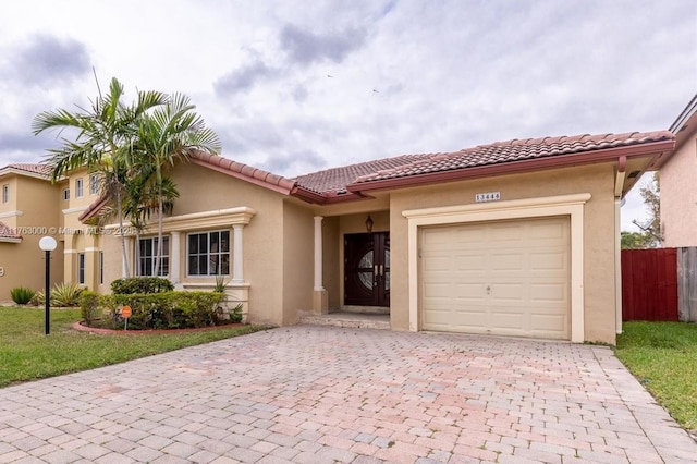 mediterranean / spanish-style home featuring decorative driveway, a garage, a tile roof, and stucco siding