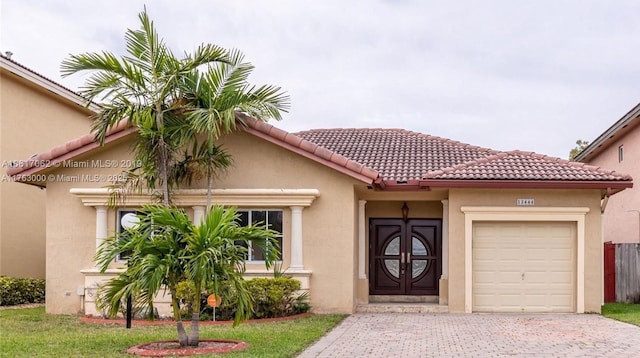 view of front facade with a tiled roof, decorative driveway, a garage, and stucco siding