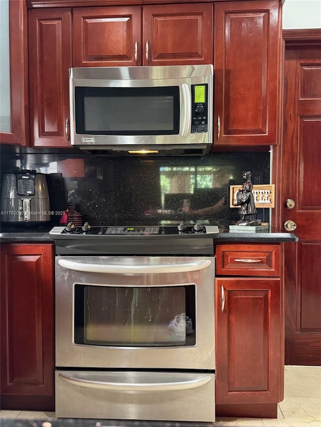 kitchen with dark countertops, decorative backsplash, dark brown cabinets, and appliances with stainless steel finishes