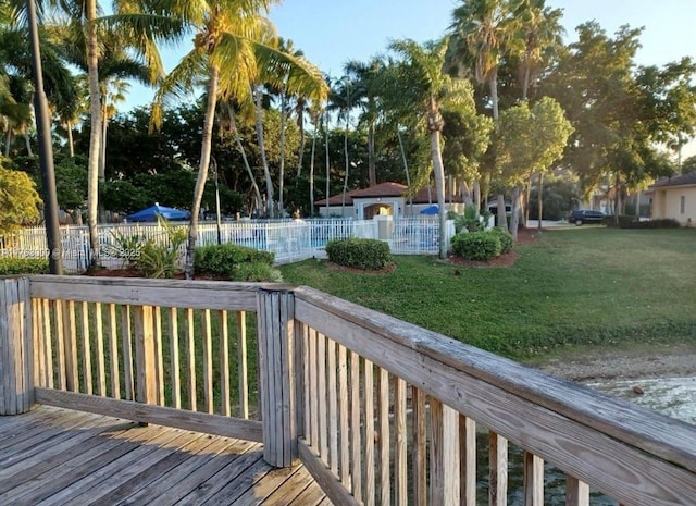 deck with a swimming pool, fence, and a lawn