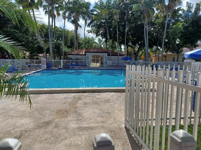 community pool with a patio and fence