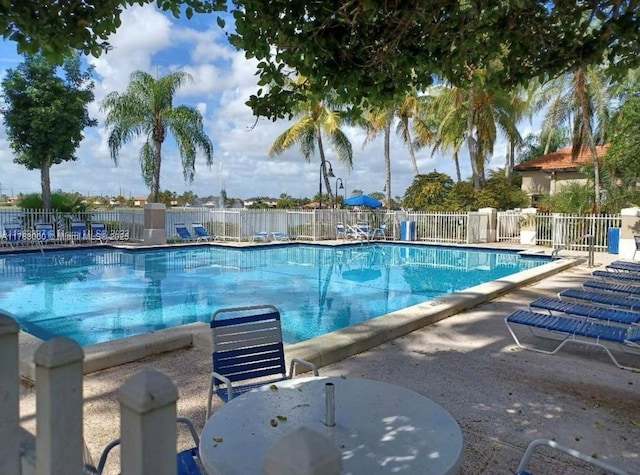 community pool with a patio area and fence