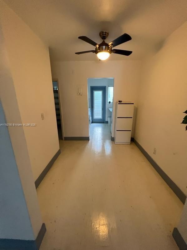 unfurnished room with a ceiling fan and baseboards