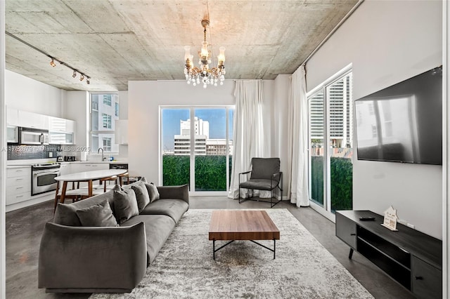 living area featuring a chandelier, rail lighting, and concrete flooring