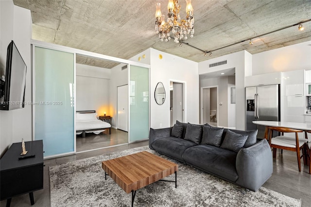 living area featuring visible vents, an inviting chandelier, and finished concrete floors