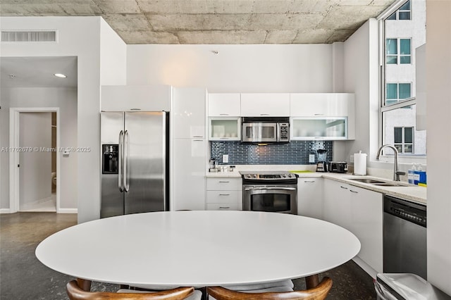 kitchen with visible vents, a sink, white cabinetry, appliances with stainless steel finishes, and decorative backsplash