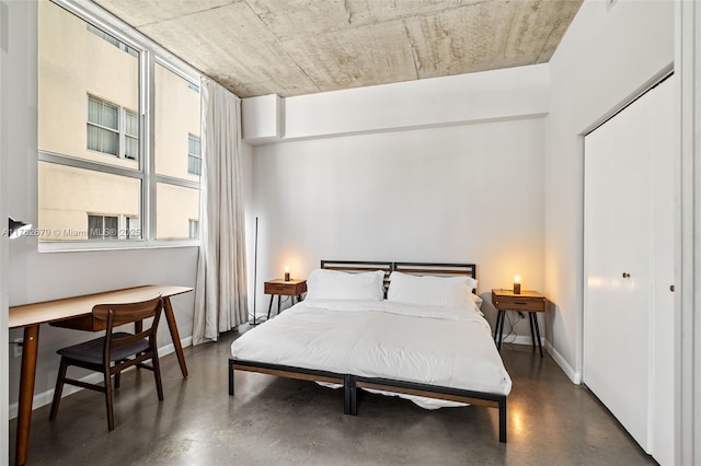 bedroom featuring baseboards and concrete flooring