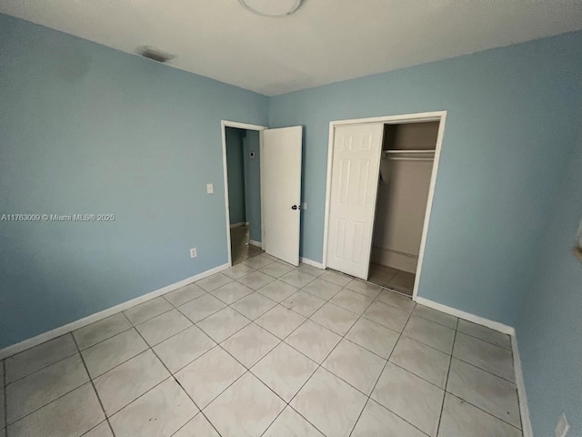 unfurnished bedroom featuring light tile patterned floors, visible vents, baseboards, and a closet