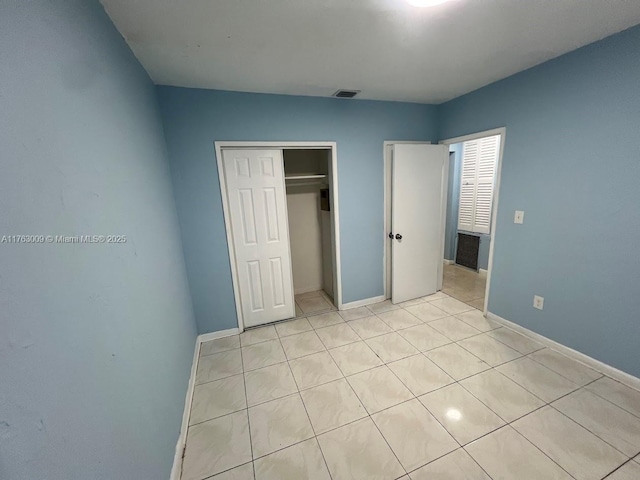 unfurnished bedroom featuring light tile patterned floors, baseboards, visible vents, and a closet