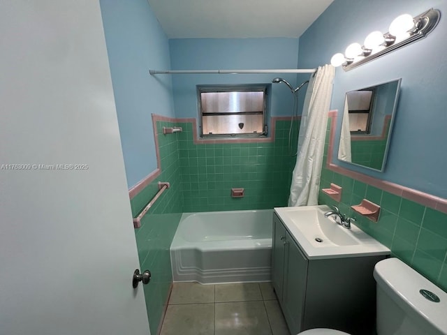 bathroom with a wainscoted wall, shower / bath combo, tile patterned flooring, tile walls, and toilet