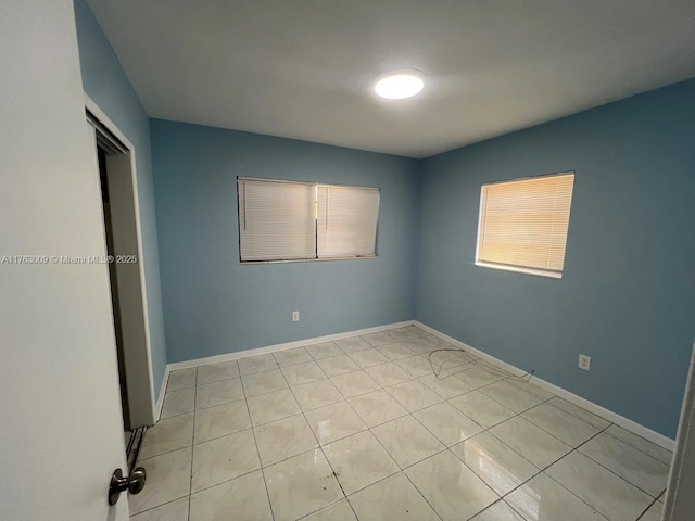 unfurnished room with light tile patterned floors and baseboards