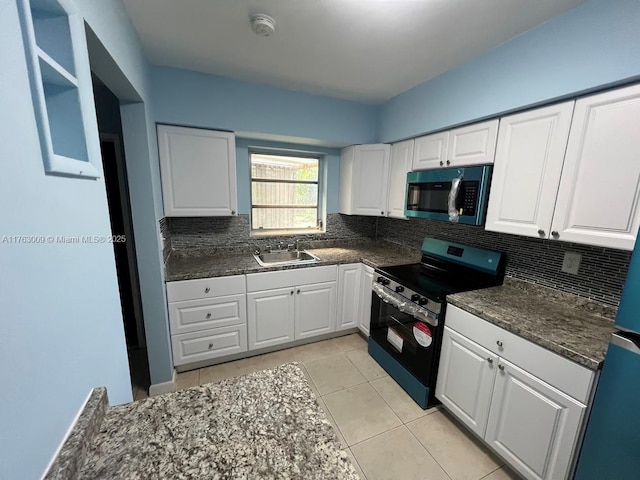 kitchen with tasteful backsplash, light tile patterned flooring, white cabinets, stainless steel appliances, and a sink