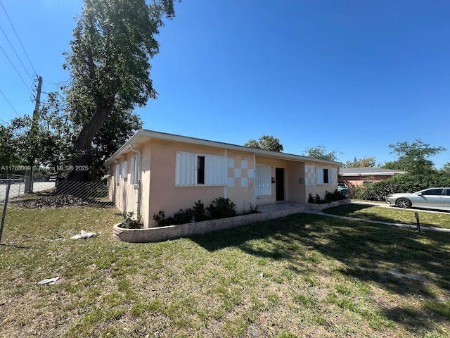 view of front of home featuring stucco siding, a front lawn, and fence