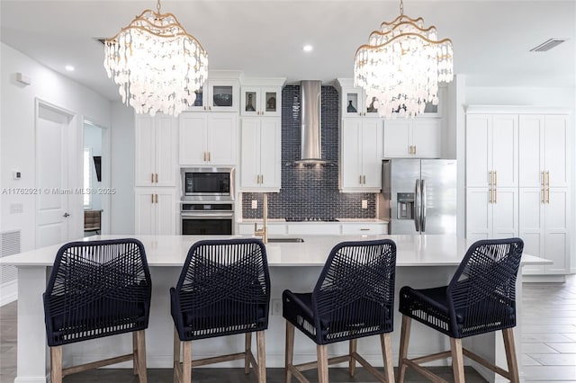 kitchen with visible vents, a chandelier, light countertops, stainless steel appliances, and wall chimney exhaust hood