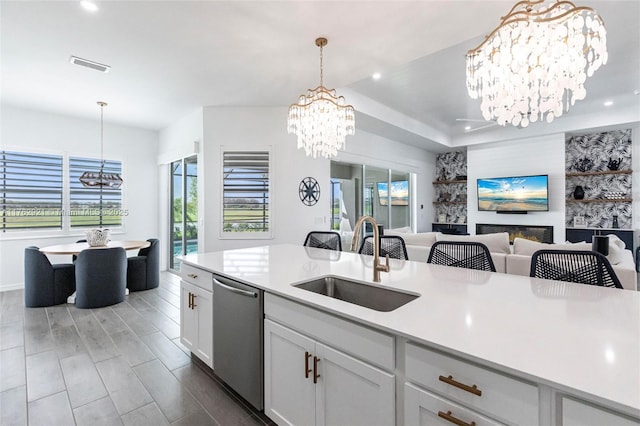 kitchen with visible vents, a sink, open floor plan, an inviting chandelier, and dishwasher