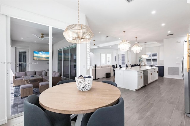 dining area featuring light wood finished floors, visible vents, baseboards, recessed lighting, and ceiling fan with notable chandelier