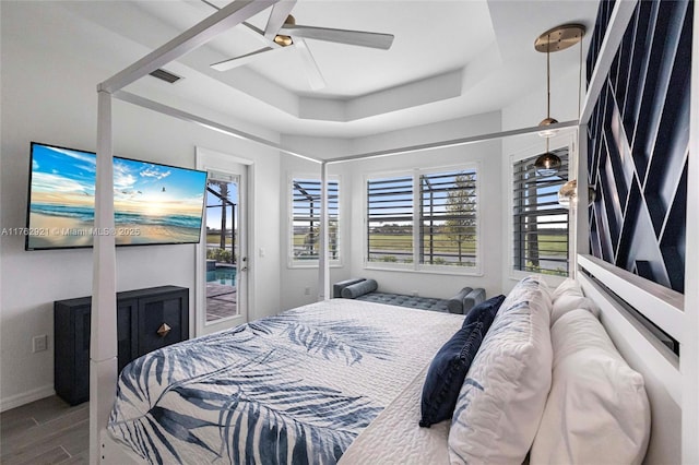 bedroom with a raised ceiling, a ceiling fan, wood finished floors, baseboards, and access to exterior