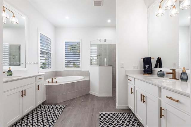 full bathroom with visible vents, two vanities, walk in shower, and a sink