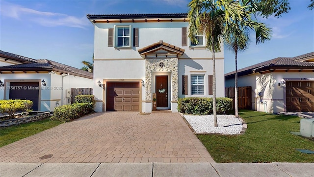 mediterranean / spanish-style home with stone siding, stucco siding, decorative driveway, and a garage