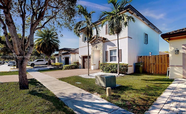 view of side of property with fence, driveway, a yard, stucco siding, and a garage