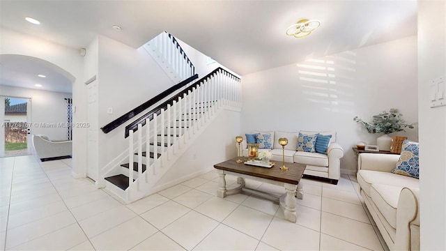 living area with tile patterned flooring, baseboards, stairway, recessed lighting, and arched walkways