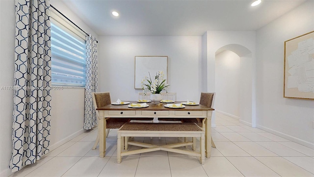 dining room featuring arched walkways, light tile patterned floors, recessed lighting, and baseboards