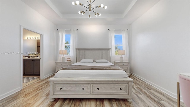 bedroom featuring a raised ceiling, multiple windows, baseboards, and light wood finished floors