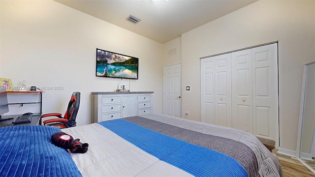 bedroom featuring wood finished floors, visible vents, and a closet