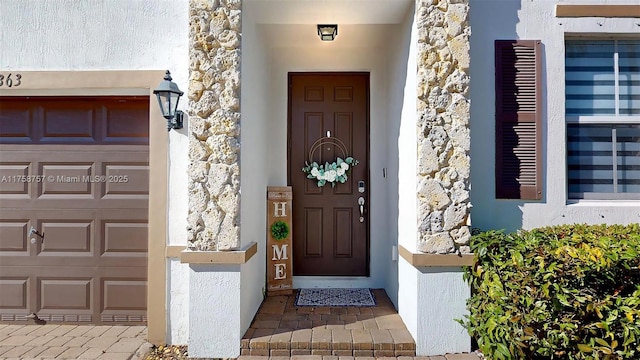 doorway to property with stucco siding and a garage