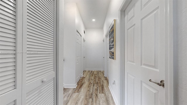 corridor featuring light wood finished floors, recessed lighting, and baseboards