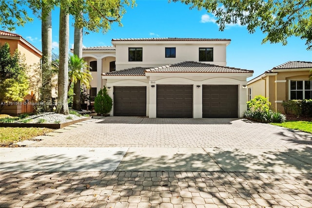 mediterranean / spanish home with a tiled roof, decorative driveway, and stucco siding