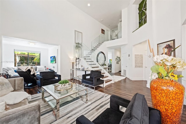 living room with stairway, wood finished floors, a high ceiling, and baseboards