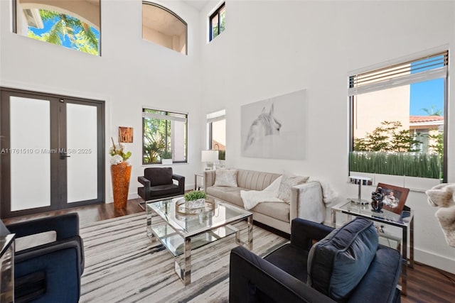 living room featuring french doors, baseboards, wood finished floors, and a towering ceiling