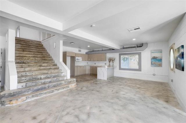 unfurnished living room featuring a sink, stairway, concrete flooring, and visible vents