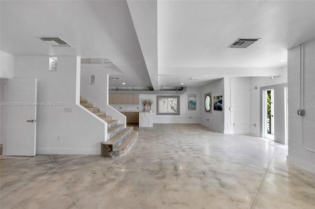 unfurnished living room featuring visible vents, finished concrete floors, and stairs