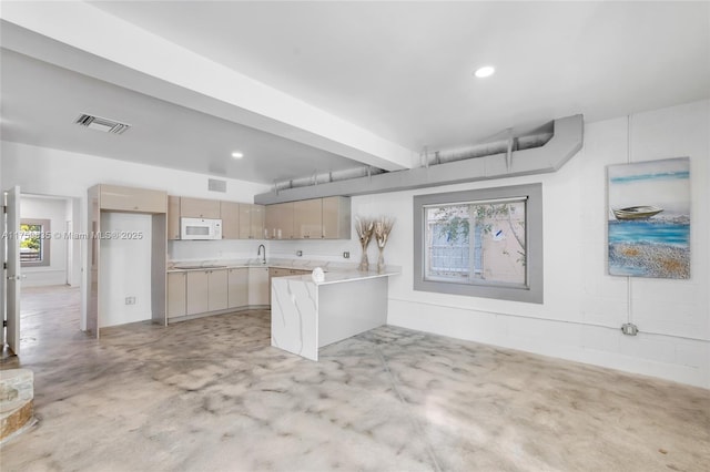 kitchen with visible vents, white microwave, concrete floors, and a peninsula