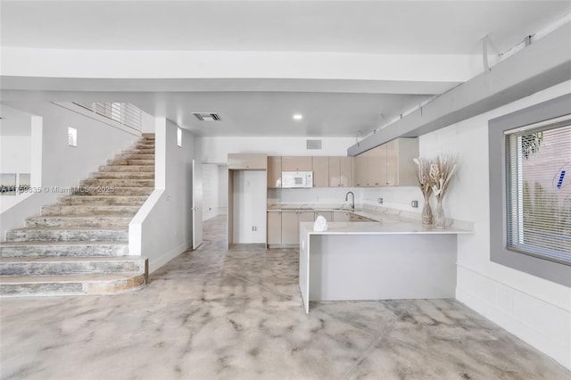 kitchen with white microwave, visible vents, a peninsula, and concrete flooring