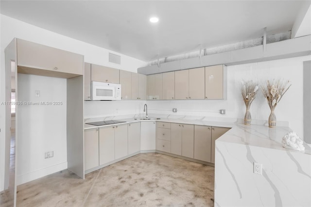 kitchen with light stone counters, white microwave, concrete floors, a sink, and black electric stovetop