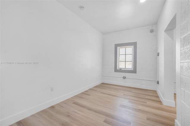 spare room featuring baseboards and light wood-style flooring