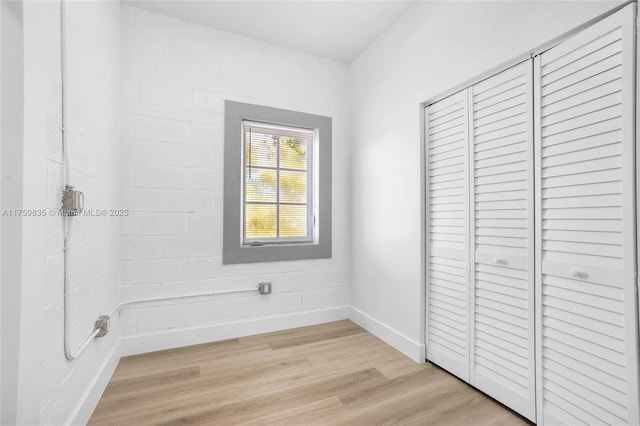 unfurnished bedroom with light wood-style flooring, baseboards, and a closet